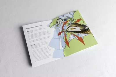 Two open greeting cards displayed on a white surface, with the left card containing text and the right card featuring a colorful illustration of a figure in winter clothing among evergreen branches and red ornaments against a yellow-green background.
