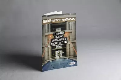 A magazine cover for Built Environment News featuring a modern sustainable architecture building with classical columns, displayed at an angle against a gray background.